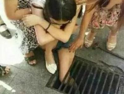 (صــورة) صينية تعلق داخل مصرف مياه لانشغالها بهاتفها المحمول