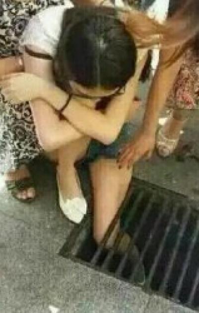 (صــورة) صينية تعلق داخل مصرف مياه لانشغالها بهاتفها المحمول