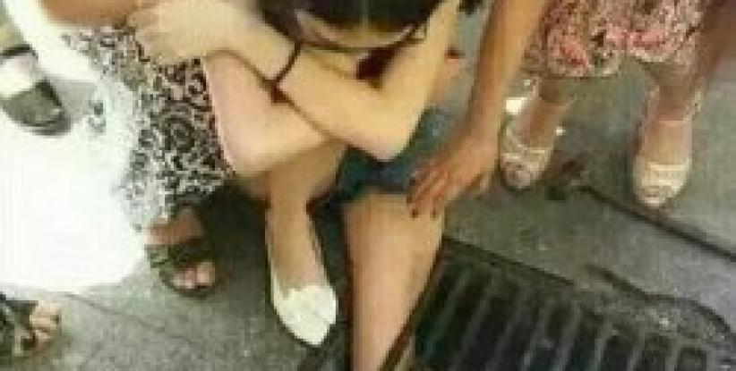 (صــورة) صينية تعلق داخل مصرف مياه لانشغالها بهاتفها المحمول