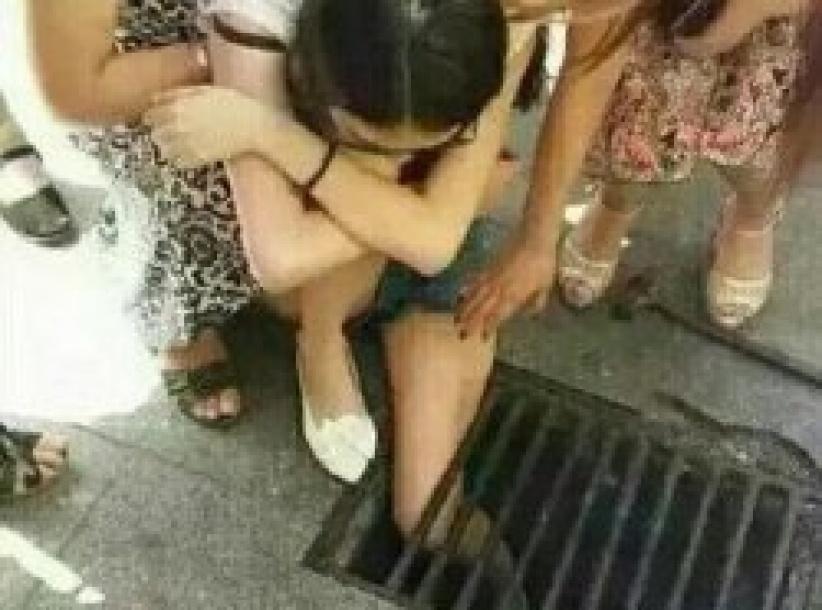 (صــورة) صينية تعلق داخل مصرف مياه لانشغالها بهاتفها المحمول