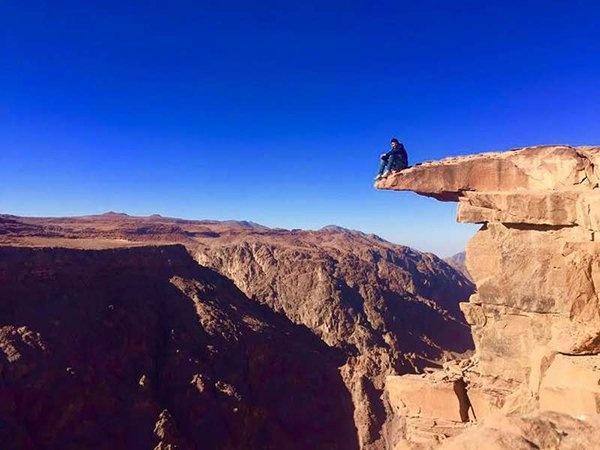 شاهد- شاب يغامر بحياته ليلتقط صور على حافة صخرة فوق ارتفاع 1050 متر